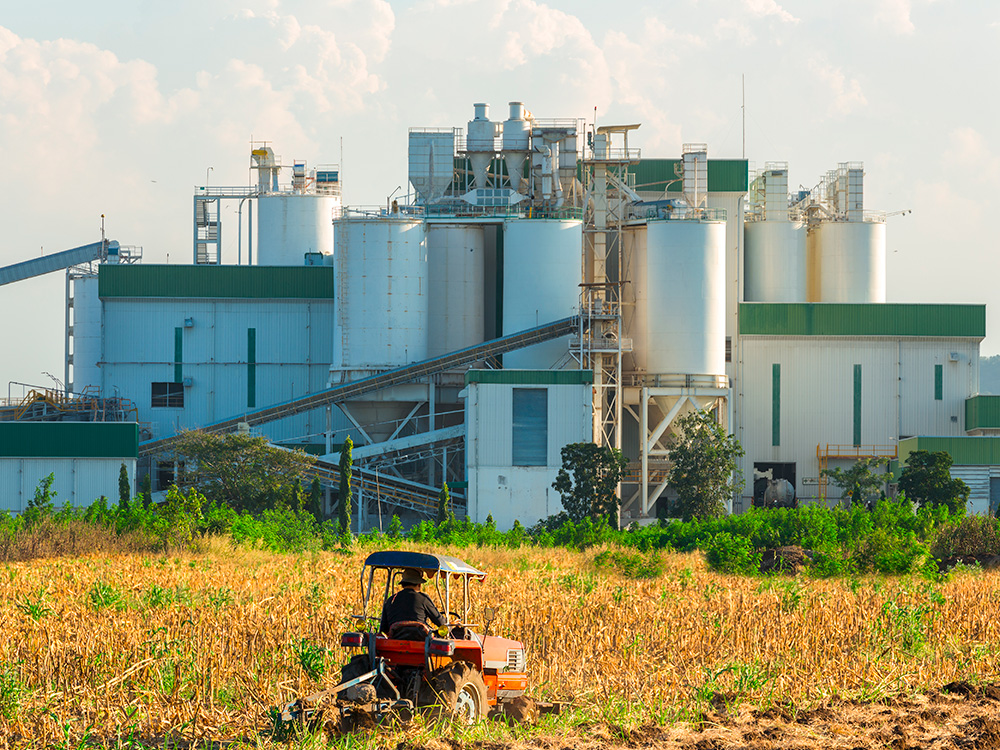 Ethanol industrial refinery with farm tractors in the foreground