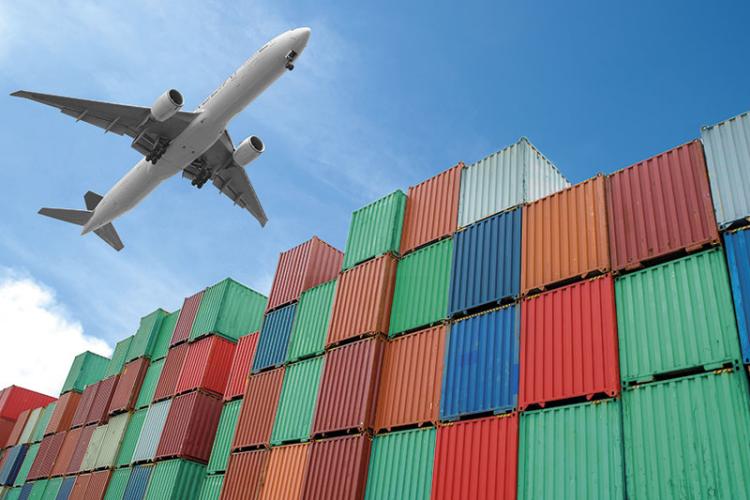 Aeroplane flying over shipping containers.