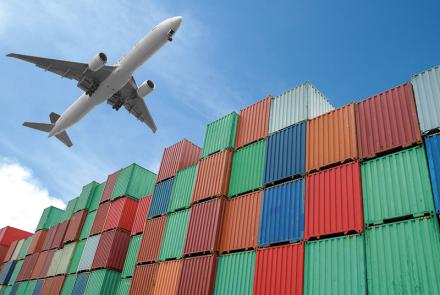 Aeroplane flying over shipping containers.